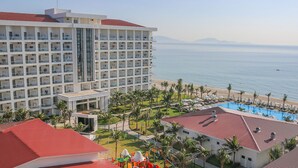 Un hôtel à plusieurs étages, doté d’une piscine et offrant une vue sur la plage.