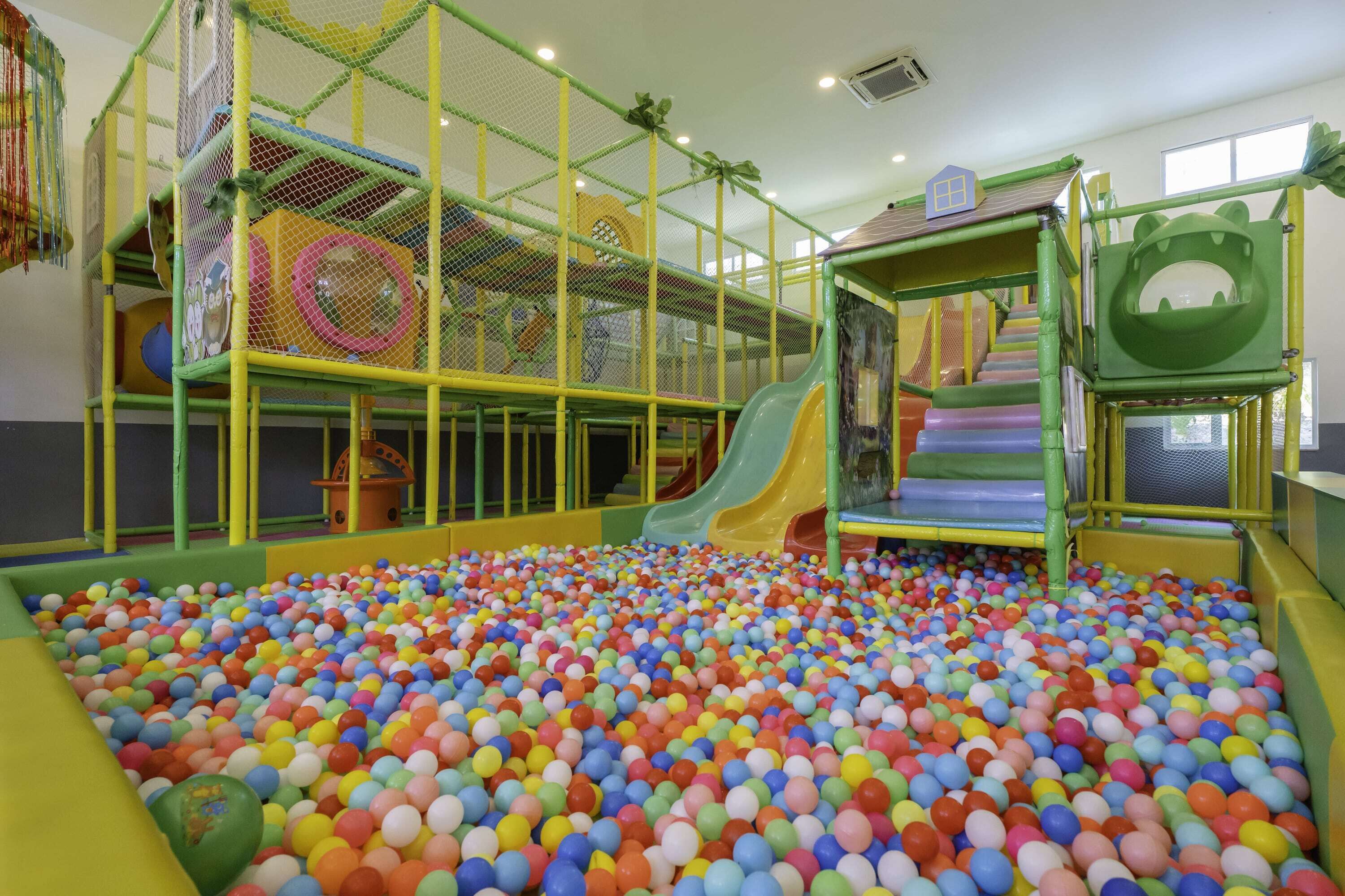 A children's play area with a ball pit, slides, and a netted climbing structure.