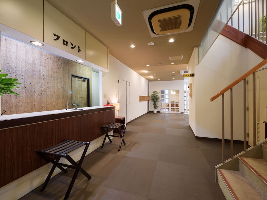 A reception area with a wooden counter, a bench, and a staircase.