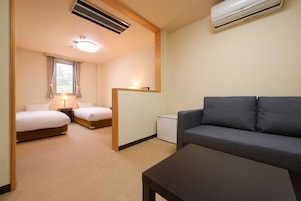 Una habitación de hotel con dos camas, un sofá, una mesita y un escritorio.