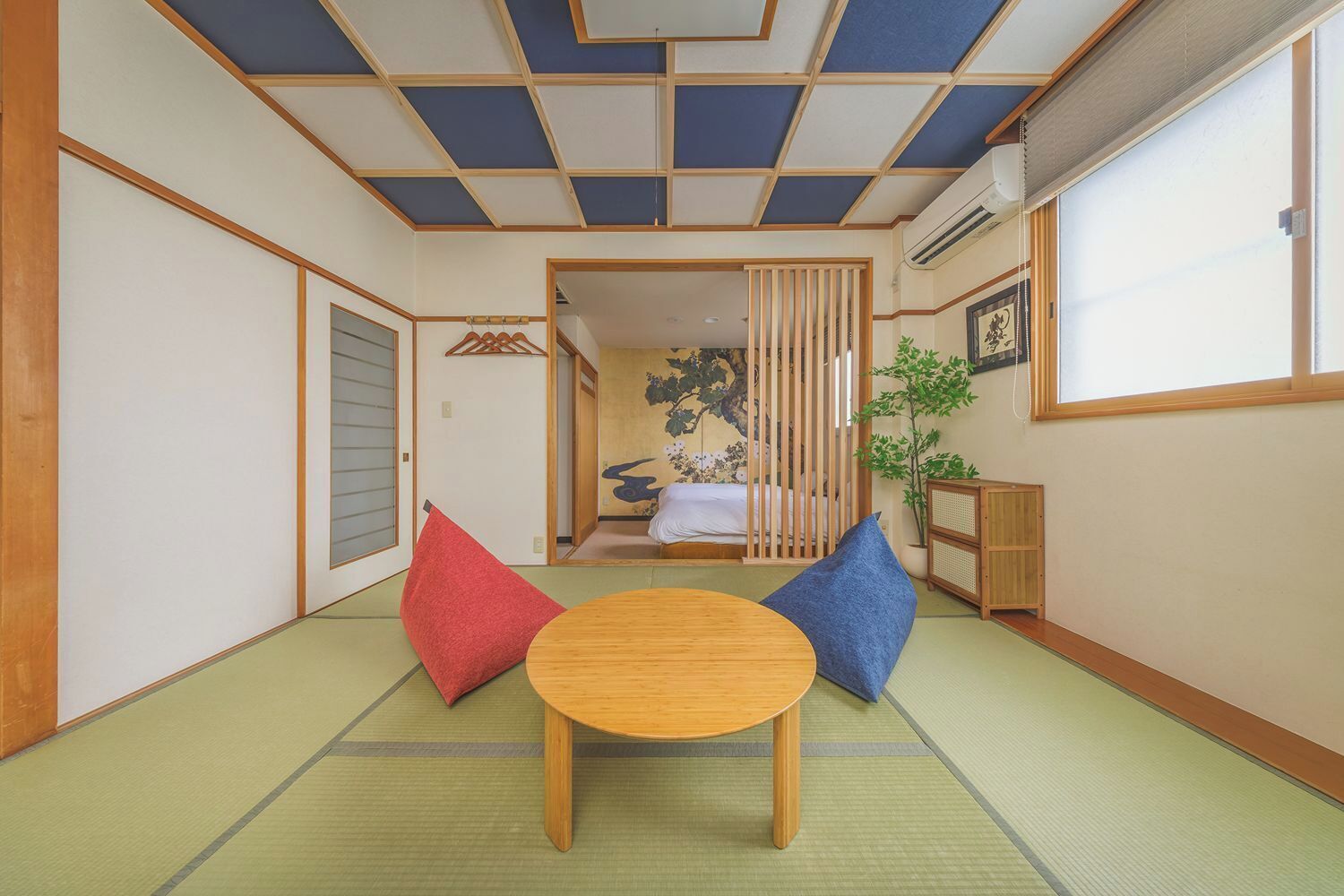 A traditional Japanese room with tatami flooring, a low wooden table, and a bed with a shoji screen backdrop.