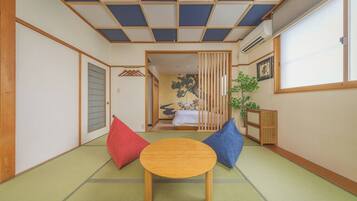 A traditional Japanese room with tatami flooring, a low wooden table, and a bed with a shoji screen backdrop.