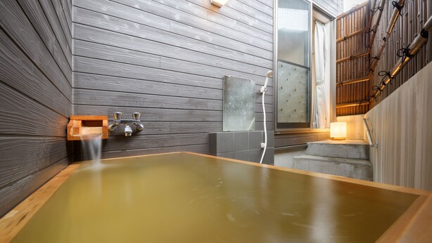 Un moderno spa con una amplia bañera de madera, cabina de ducha de vidrio y una escalera de madera.