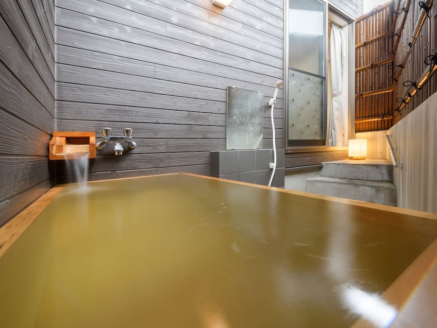 Une salle de spa moderne avec une grande baignoire en bois, une douche en verre et un escalier en bois.