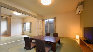 Una habitación japonesa tradicional con suelo de tatami, una mesa baja y un televisor.