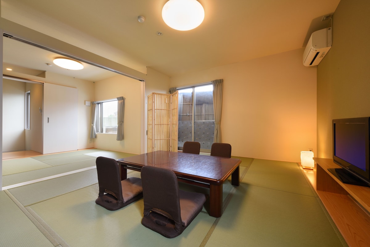 Une pièce de style japonais traditionnel, avec un sol recouvert de tatamis, une table basse et un téléviseur.