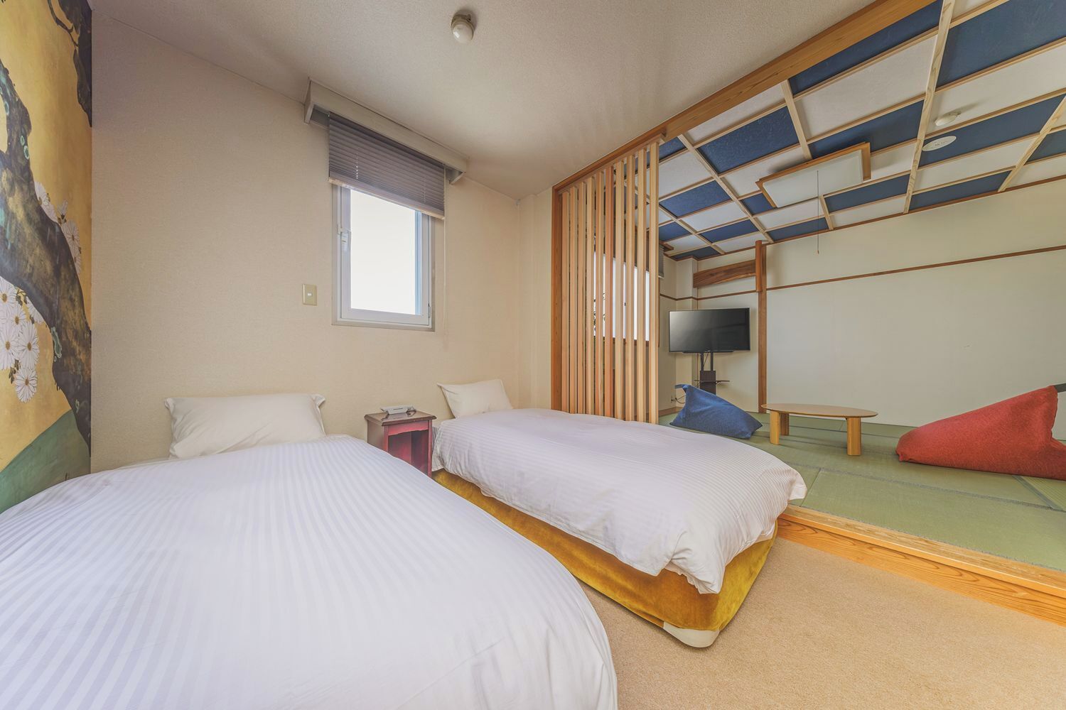 Una habitación de hotel con dos camas, una ventana con persianas, una televisión y un futón.