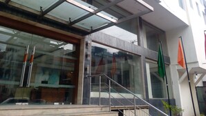 A building with a modern architectural style, featuring a glass entrance, metal railings, and a staircase leading to the entrance. - The Horizon Comforts (Bengaluru)