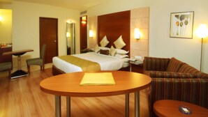 A hotel room with a bed, a desk, a chair, a sofa, and a table. - The Horizon Comforts (Bengaluru)