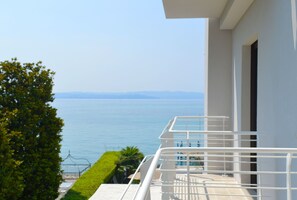 Ein Balkon mit Meerblick, einem weißen Geländer und wolkenlosem Himmel.