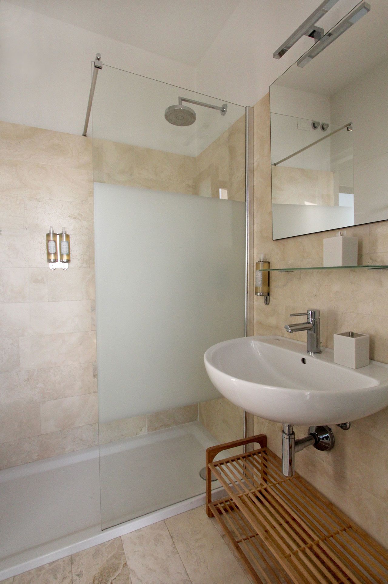 A modern bathroom with a glass shower enclosure, a white sink, and a large mirror.