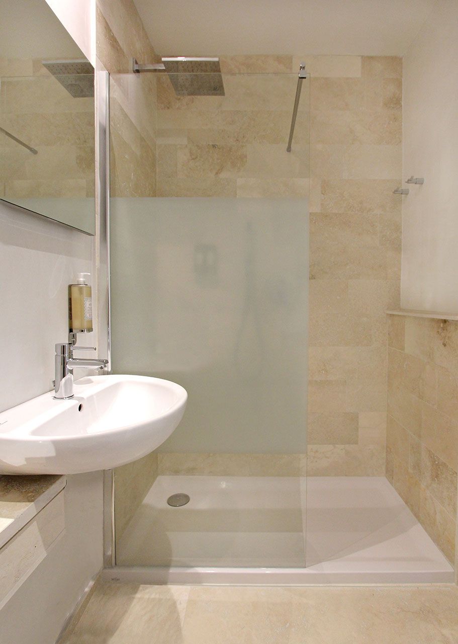 A bathroom with a glass-enclosed shower, a white sink, and a mirror.