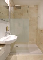 Un bagno con doccia vetrata, lavandino bianco e specchio.