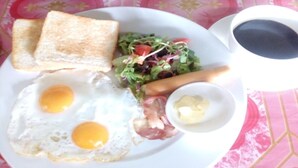 A plate with two fried eggs, toast, a salad, a small bowl of butter, and a cup of coffee. - Sokmisay Hotel・GuestHouse (Luang Prabang)