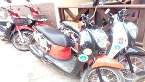 A row of scooters parked in a covered area with a wooden fence. - Sokmisay Hotel・GuestHouse (Luang Prabang)