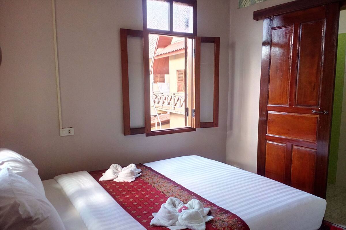 A hotel room with a bed, a window, a wardrobe, and a view of the outside balcony.