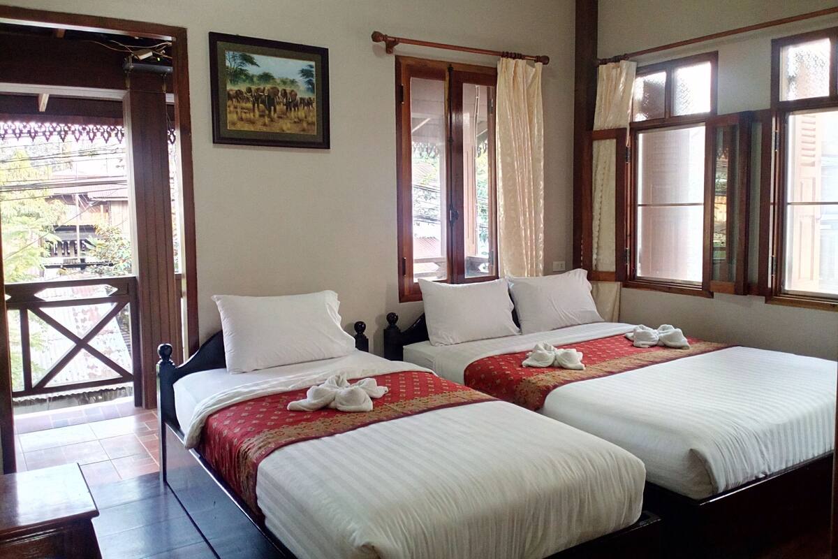 A hotel room with two beds, a balcony, and a painting on the wall.