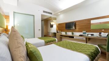 Une chambre d’hôtel avec deux lits, un bureau avec un ordinateur, une télévision et une petite plante.