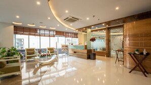 A modern hotel lobby with a reception desk, seating area, and large windows. - Rosewood Apartment Hotel - Gurgaon (Gurugram)