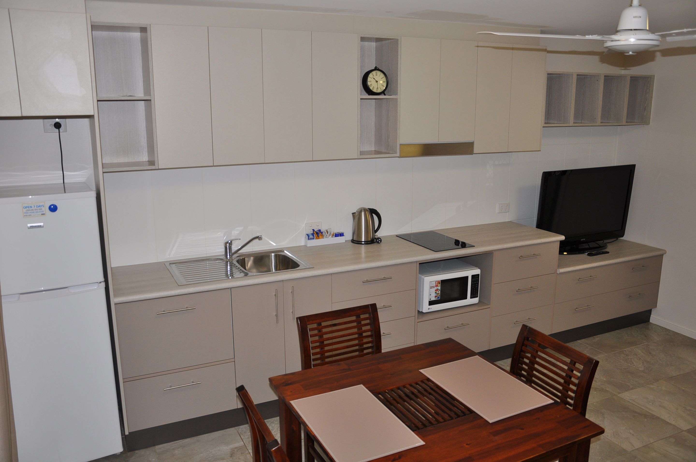 A compact kitchen with a refrigerator, microwave, sink, and a dining area with a table and chairs.