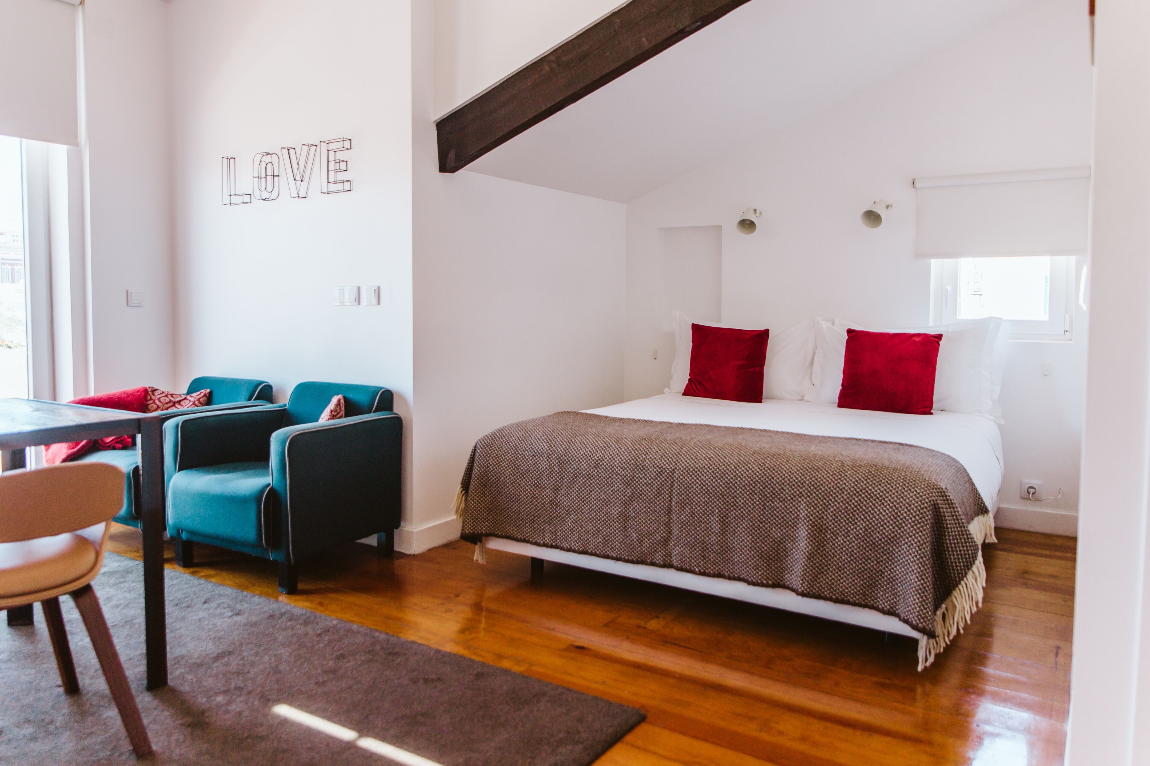 Un dormitorio con una cama, un sofá, una silla y una pared con la palabra 'LOVE'.