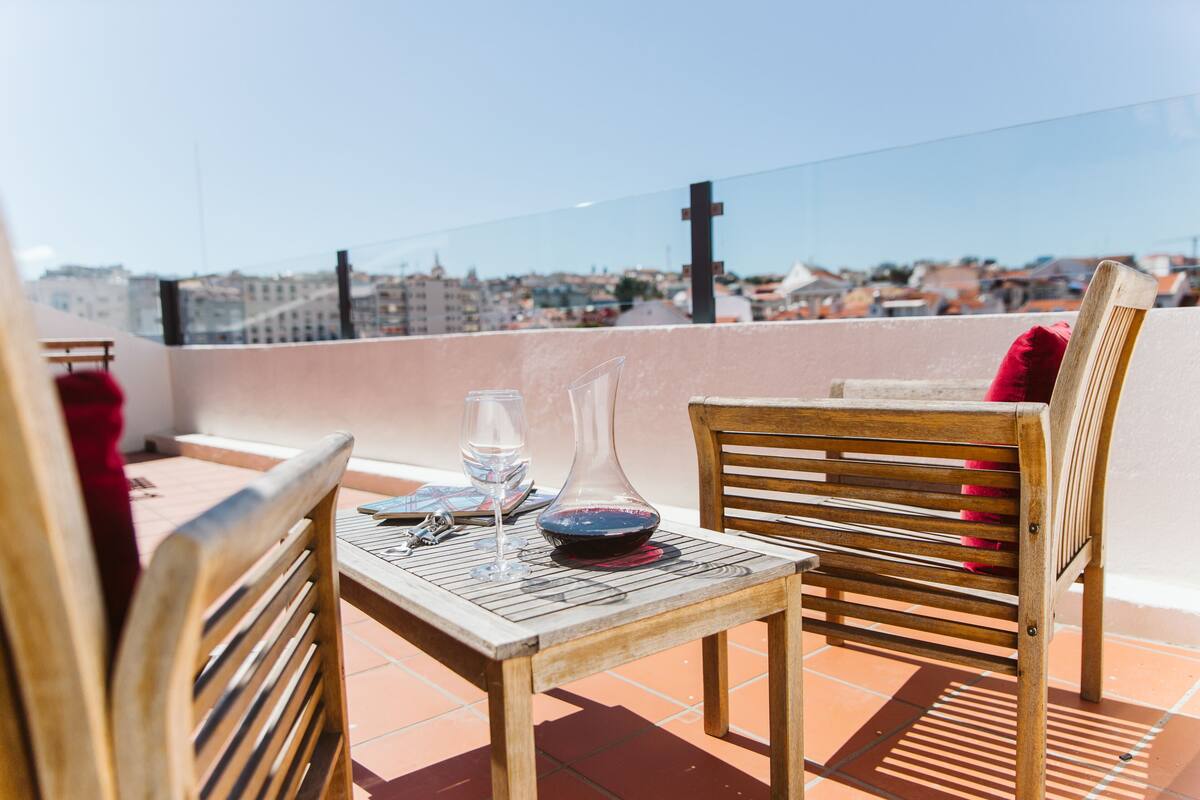 A terrace with a table, chairs, and a view of a cityscape.