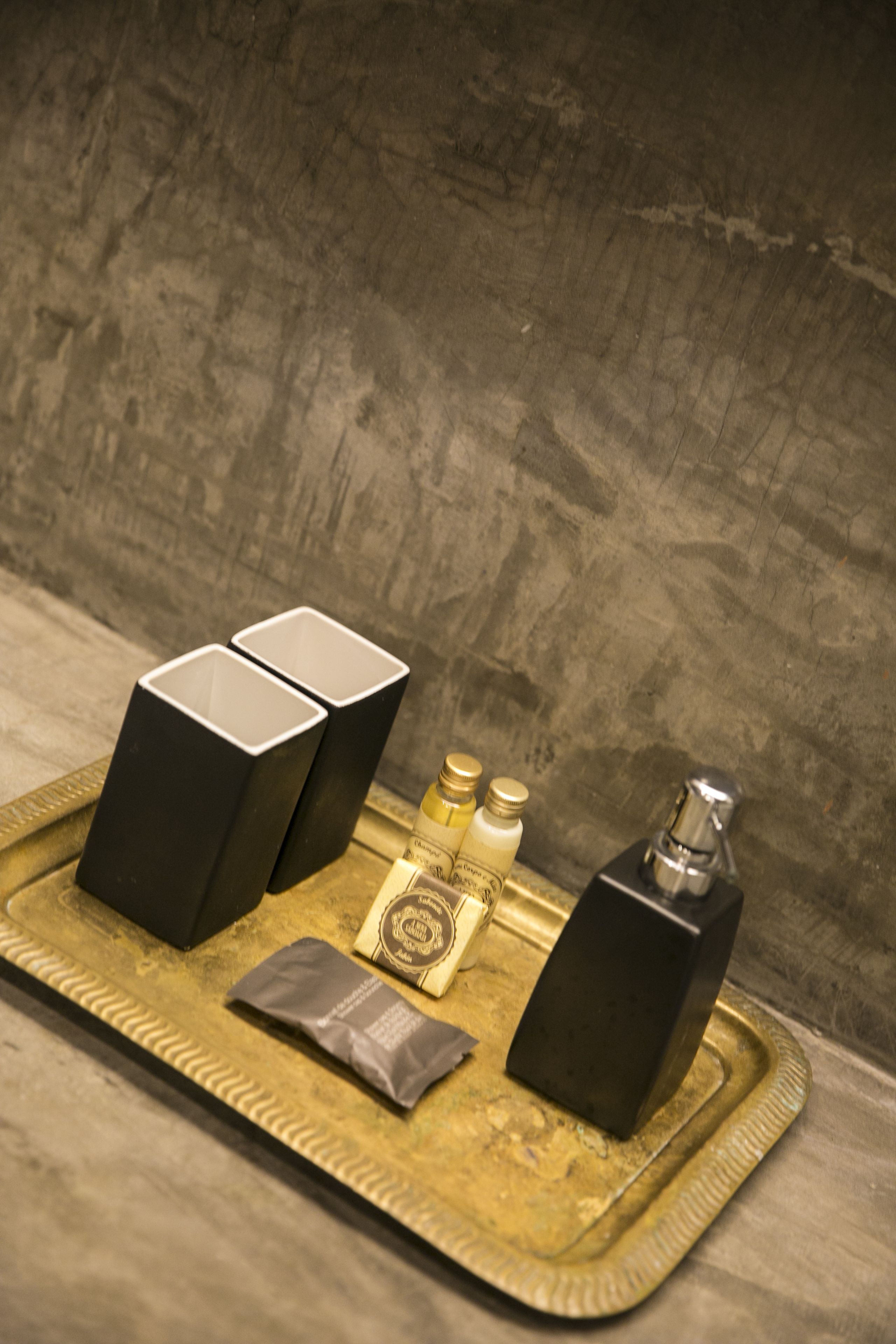 A tray with black and white boxes, a small bottle, a silver container, and a gray pouch.