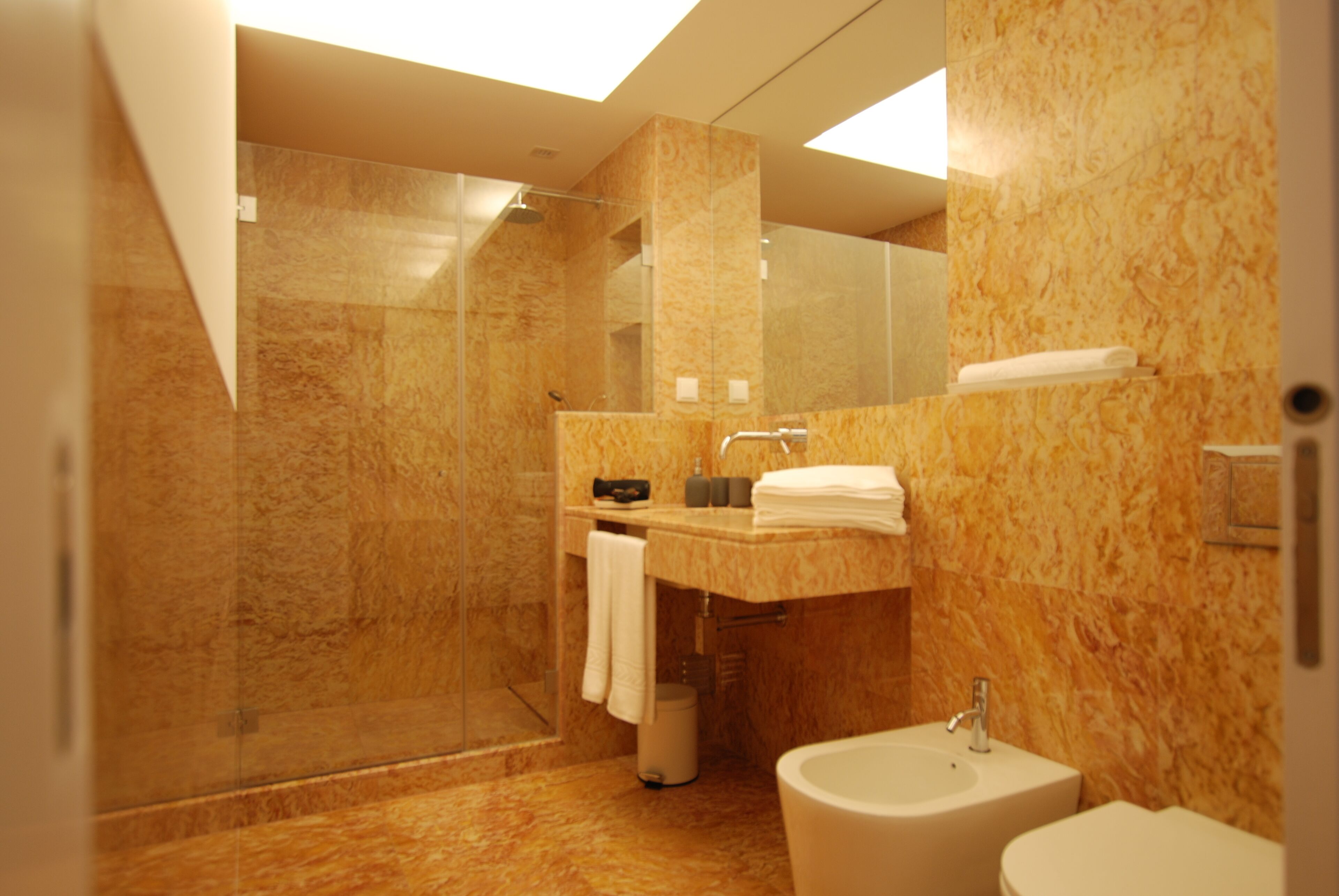 Un baño moderno con ducha de vidrio, lavamanos y bidé.