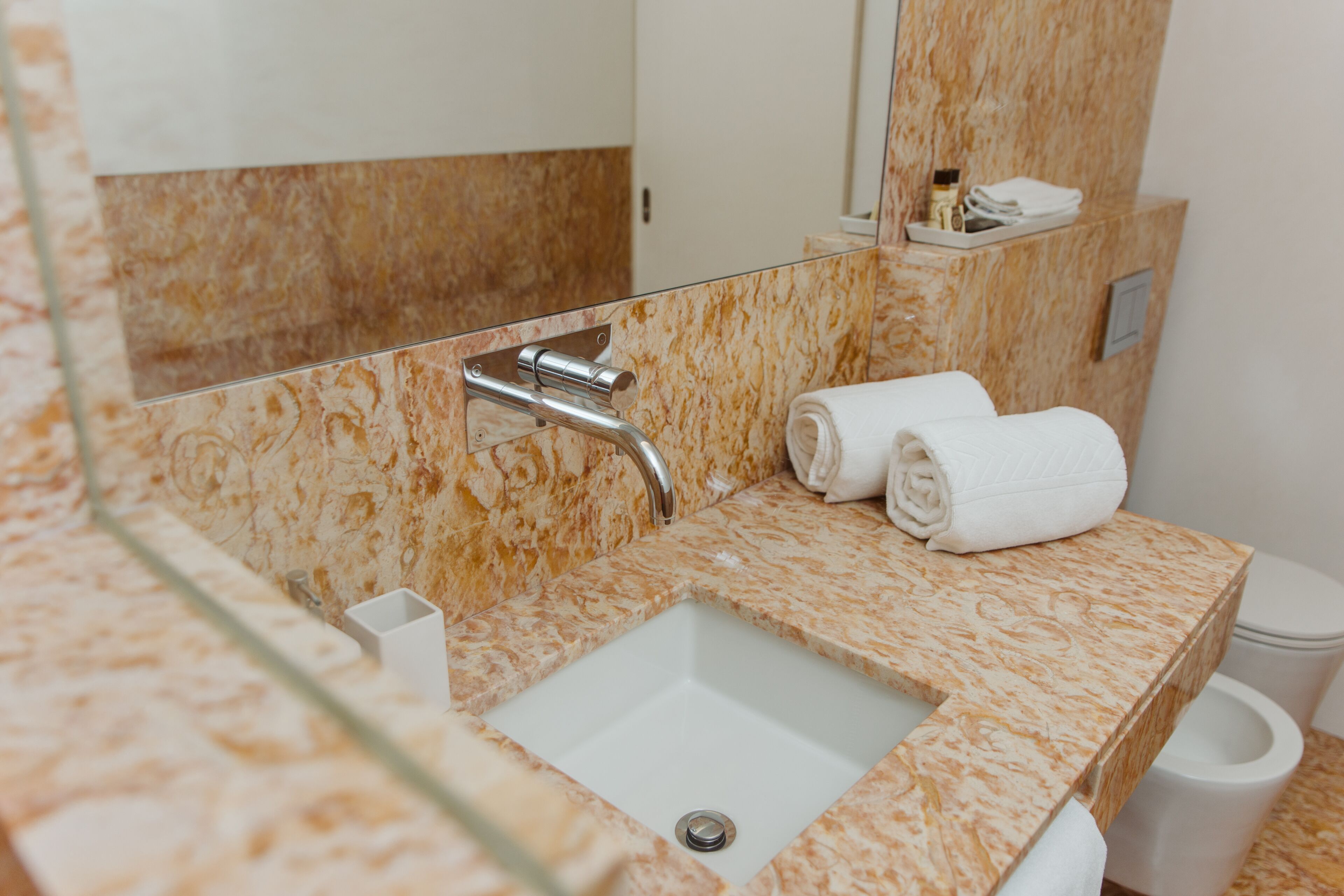 Un bany amb un lavabo de marbre, un mirall i un vàter.