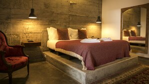A bedroom with a large bed, a wooden headboard, a red armchair, and a mirror on the wall. - 54 Santa Catarina Boutique Aparthotel (Lisbon)