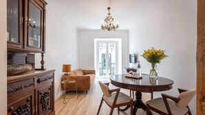A dining area with a round table, chairs, a chandelier, and a cabinet with bottles. - 54 Santa Catarina Boutique Aparthotel (Lisbon)