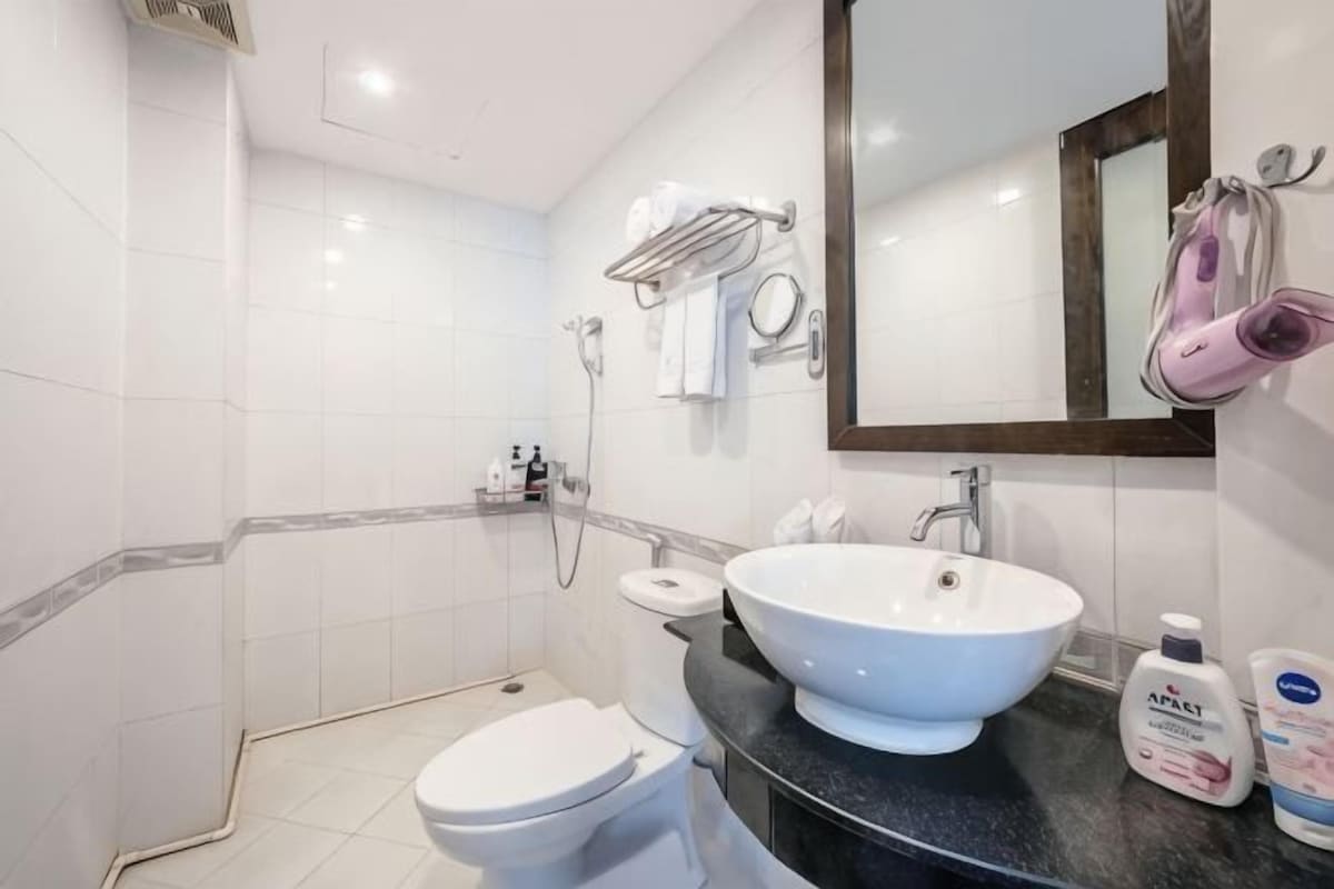 A bathroom with a white toilet, a sink, a mirror, and a shower area.