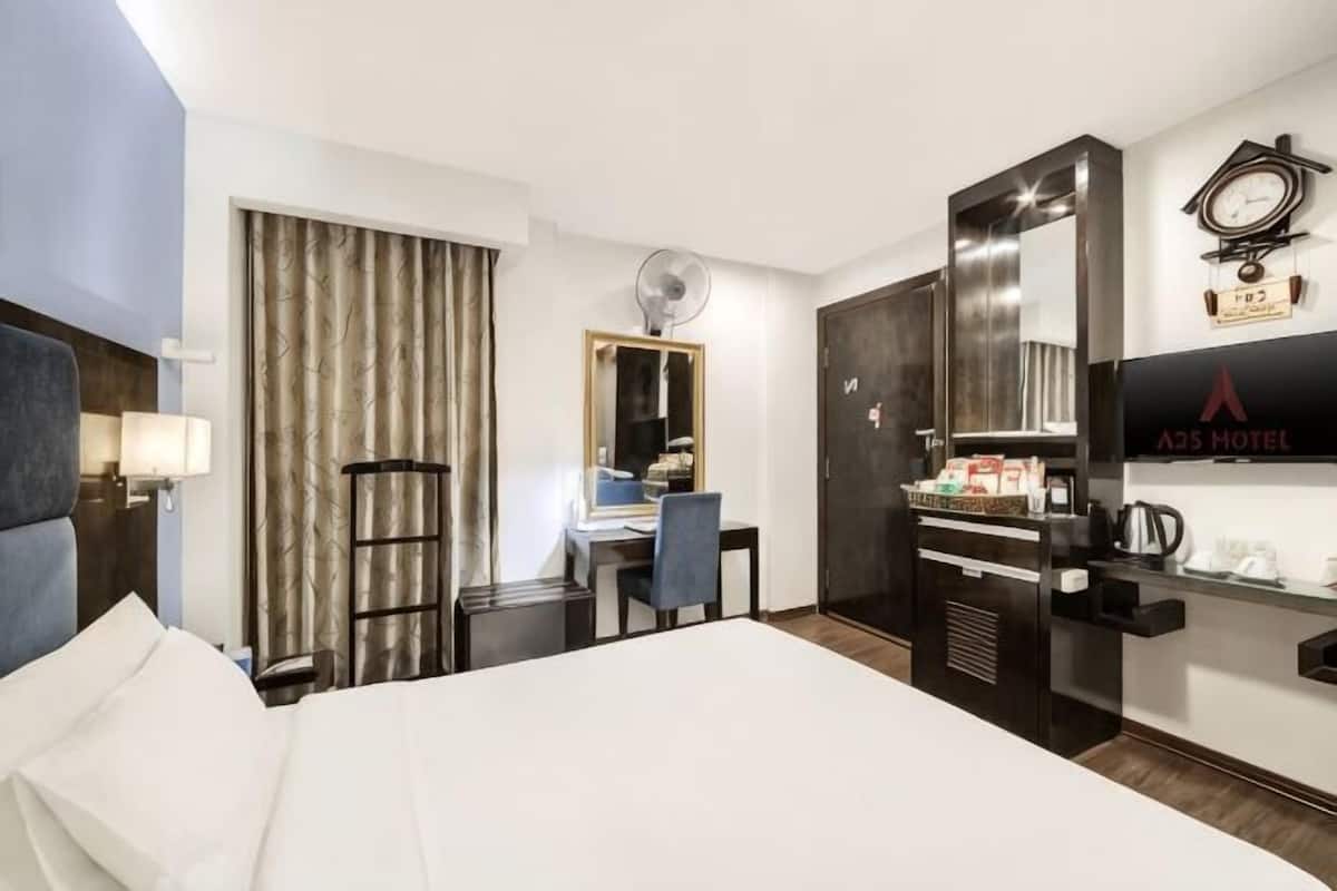 Une chambre d’hôtel avec un lit, un bureau, une chaise et une horloge au mur.