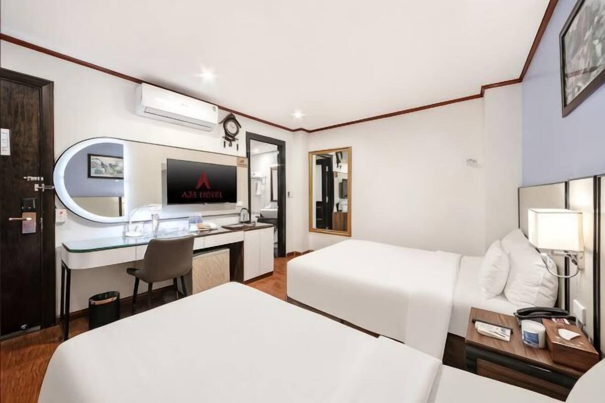 Une chambre d’hôtel comprenant un lit, un bureau avec un ordinateur, une chaise, une télévision et une table de chevet avec une lampe.