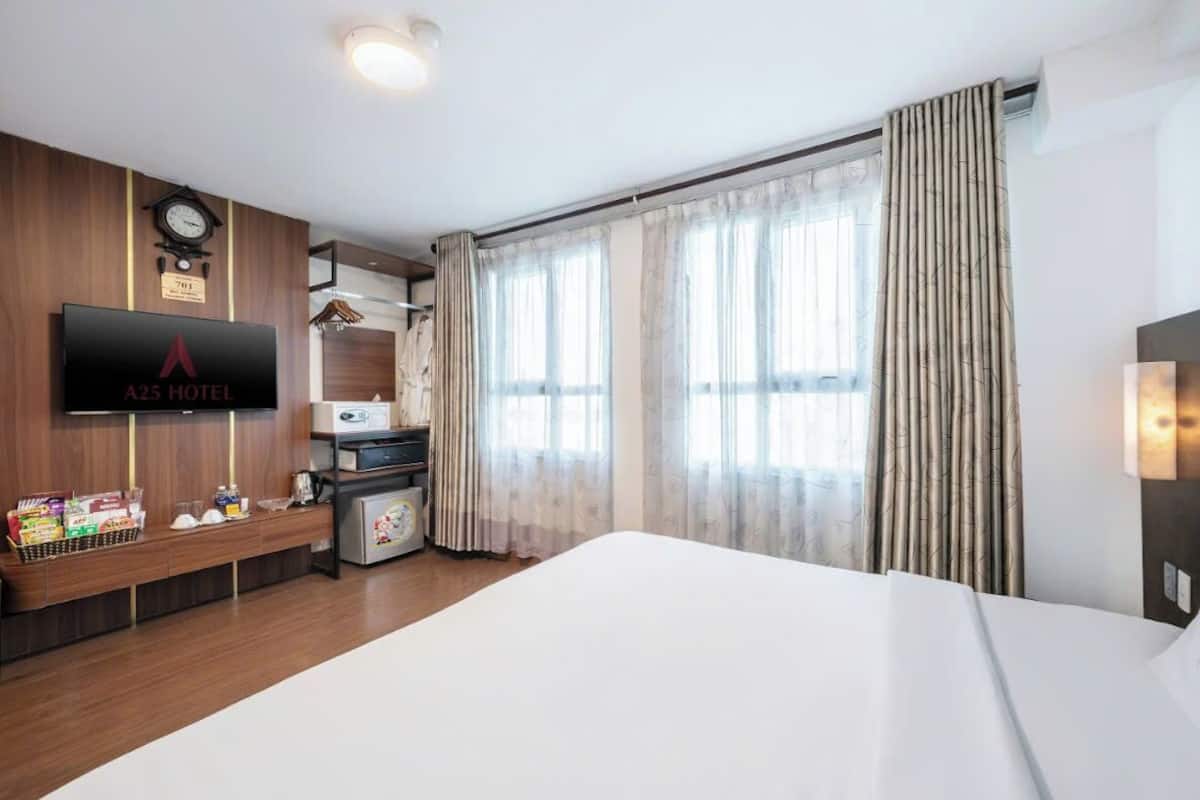 Une chambre d’hôtel équipée d’un lit, d’une télévision, d’une horloge et d’un mini-bar.