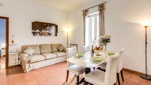 Un salon avec un canapé, une table à manger, des chaises et un tableau accroché au mur.