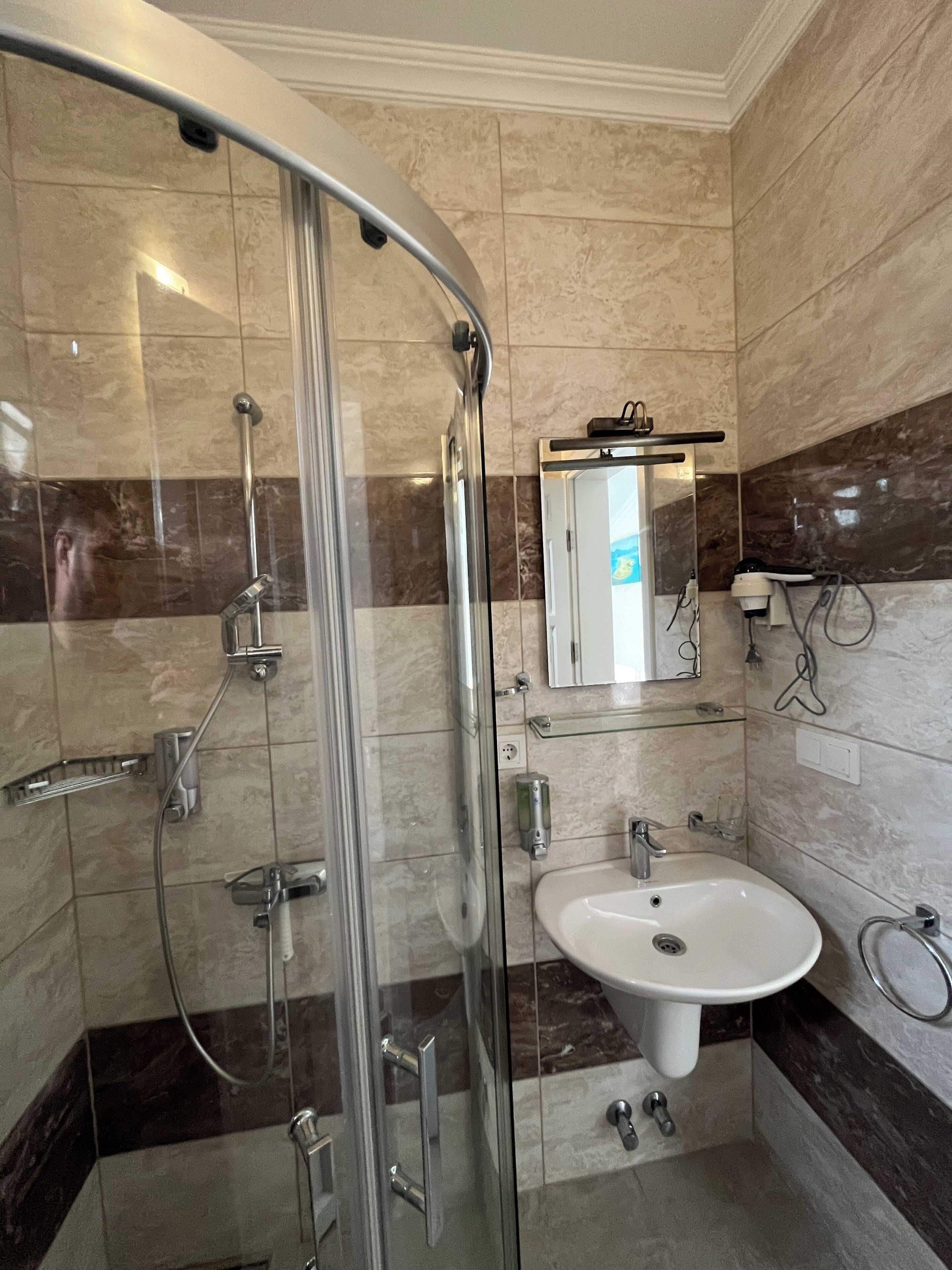 A modern bathroom with a glass shower enclosure, a white sink, and a mirror above the sink.