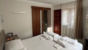 Une chambre d’hôtel avec un lit, une machine à café, un porte-serviettes et une fenêtre avec des rideaux.