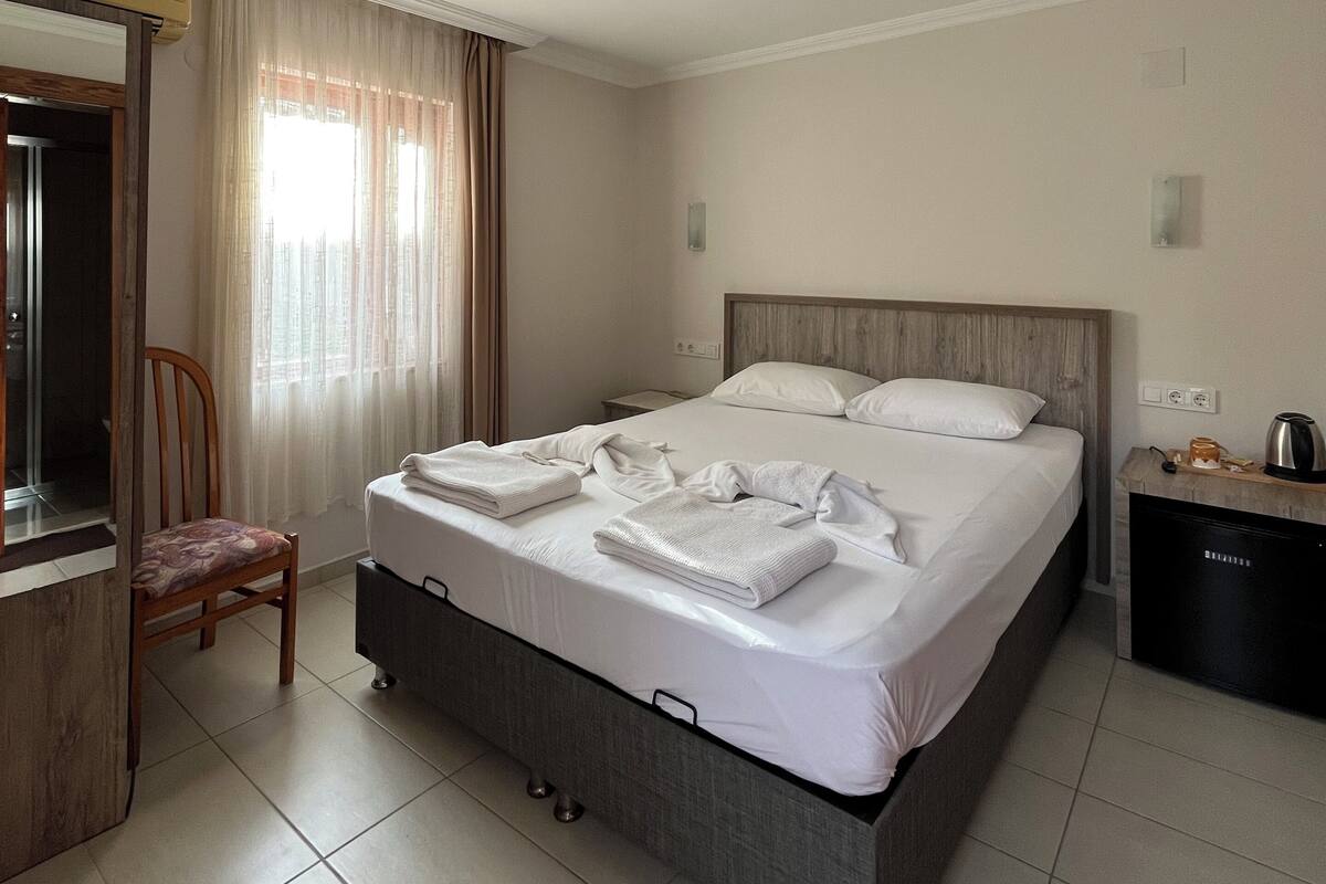 A hotel room with a bed, a chair, a desk, a coffee maker, and a nightstand.