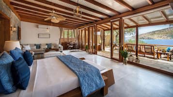 Un dormitorio espacioso con una cama grande, un ventilador de techo y vistas al mar.