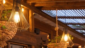 A bar area with wooden shelves, hanging light fixtures, and a variety of bottles and fruits. - Karia Bel Hotel & Restaurant - Adults Only (Marmaris)