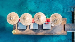 An aerial view of a wooden deck with four umbrellas, a small table, and a chair. - Karia Bel Hotel & Restaurant - Adults Only (Marmaris)