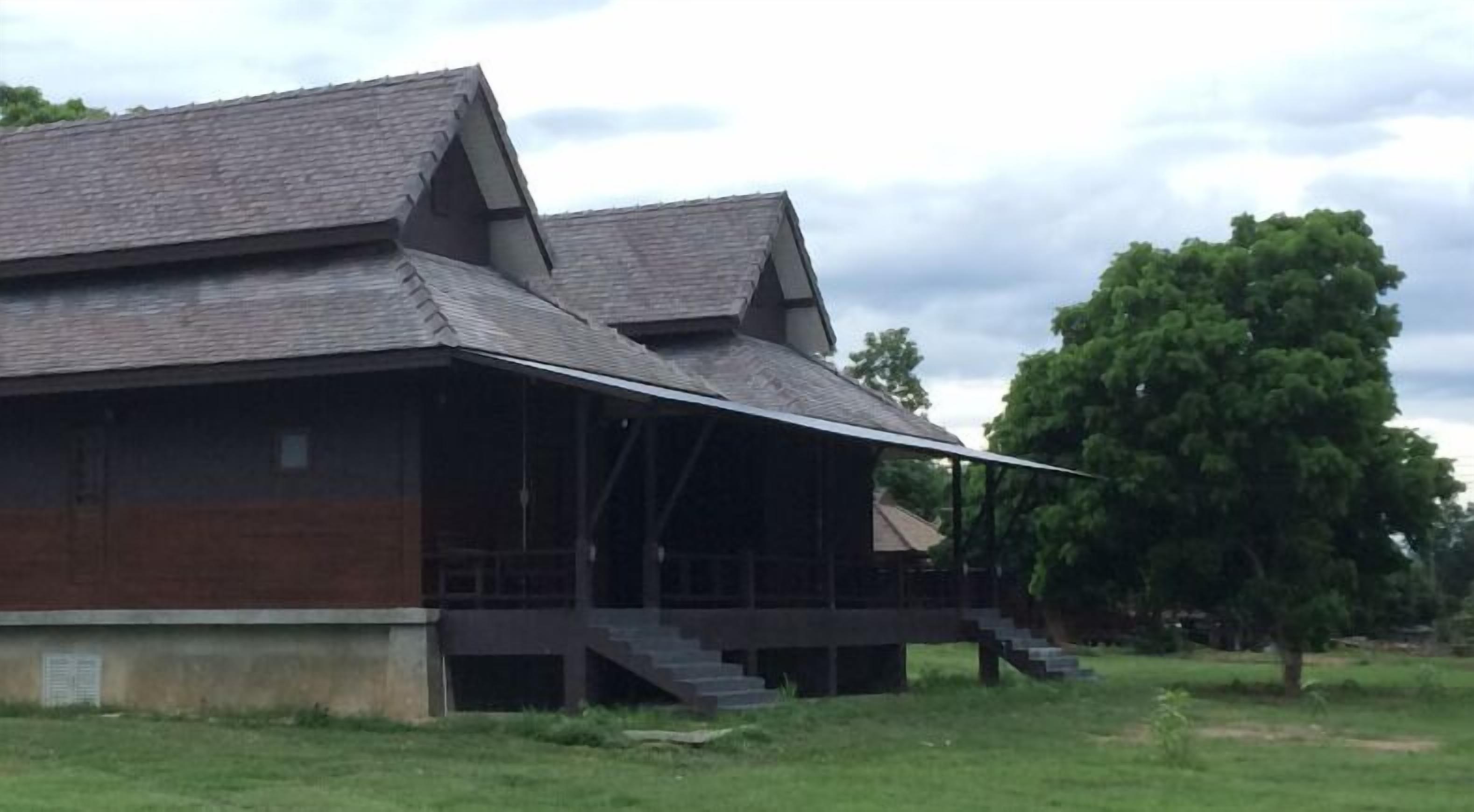 A large, two-story wooden building with a steeply pitched roof and a covered porch.
