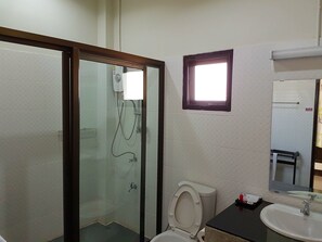 A bathroom with a glass-enclosed shower, a toilet, a sink, and a small window. - Phutawanpundao (Mae Taeng)