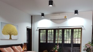 Quarto com cama de madeira, uma janela ampla com vista para árvores e um ventilador de teto.