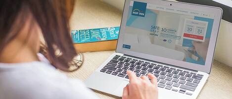 Un portátil mostrando un sitio web de reservas de hotel con una promoción de 'Safe Stay'.