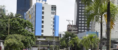 A hotel with a prominent 'HOP INN' sign, surrounded by tall buildings and palm trees.