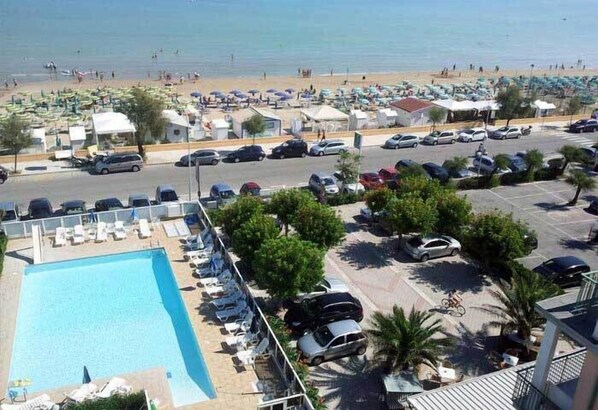 Un hotel frente a la playa con piscina, aparcamiento y acceso directo a la playa.