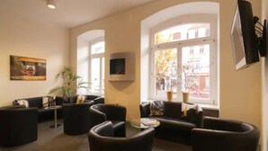 A modern living room with black leather sofas, a glass coffee table, and a large window with a view of buildings outside. - GuestHouse Heidelberg (Heidelberg)