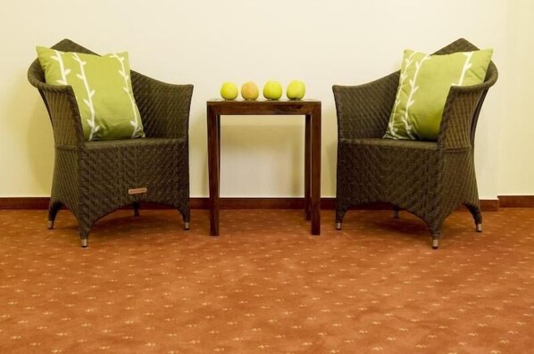 Two wicker armchairs with green cushions, a small wooden table with four apples, and a patterned carpet. - GuestHouse Heidelberg (Heidelberg)
